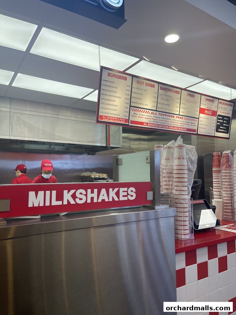 A Five Guys restaurant menu board displaying burgers, hot dogs, sandwiches, fries, drinks, and milkshakes.