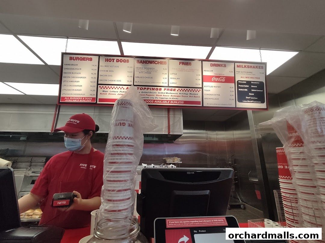 A Five Guys menu board displaying burgers, hot dogs, sandwiches, fries, drinks, and milkshakes.
