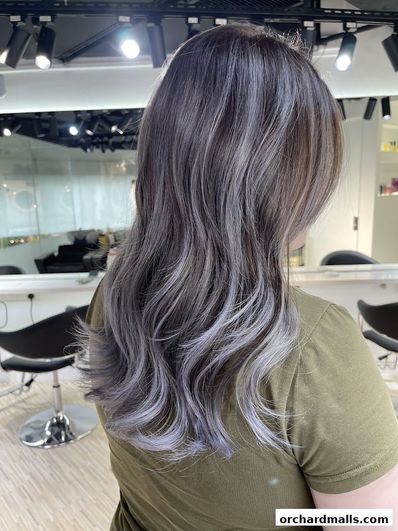 A woman with stylish grey and purple ombre hair in a modern hair studio.
