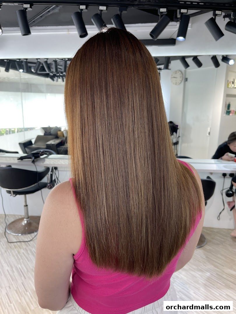 A person with long, straight, brown hair with subtle highlights in a hair studio.