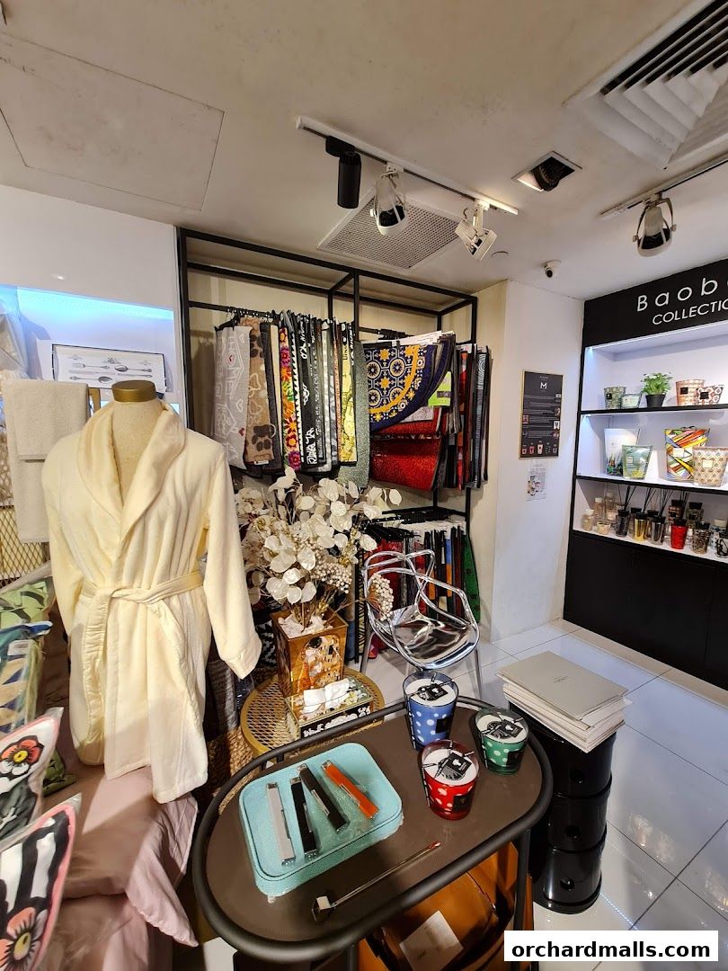 Interior view of a shop displaying bathrobes, scarves, candles, and decorative items.