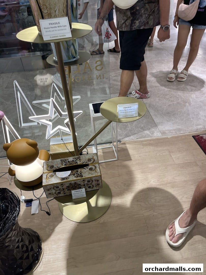 A display stand with decorative items and a 'Fragile' sign from Flaming Queen.