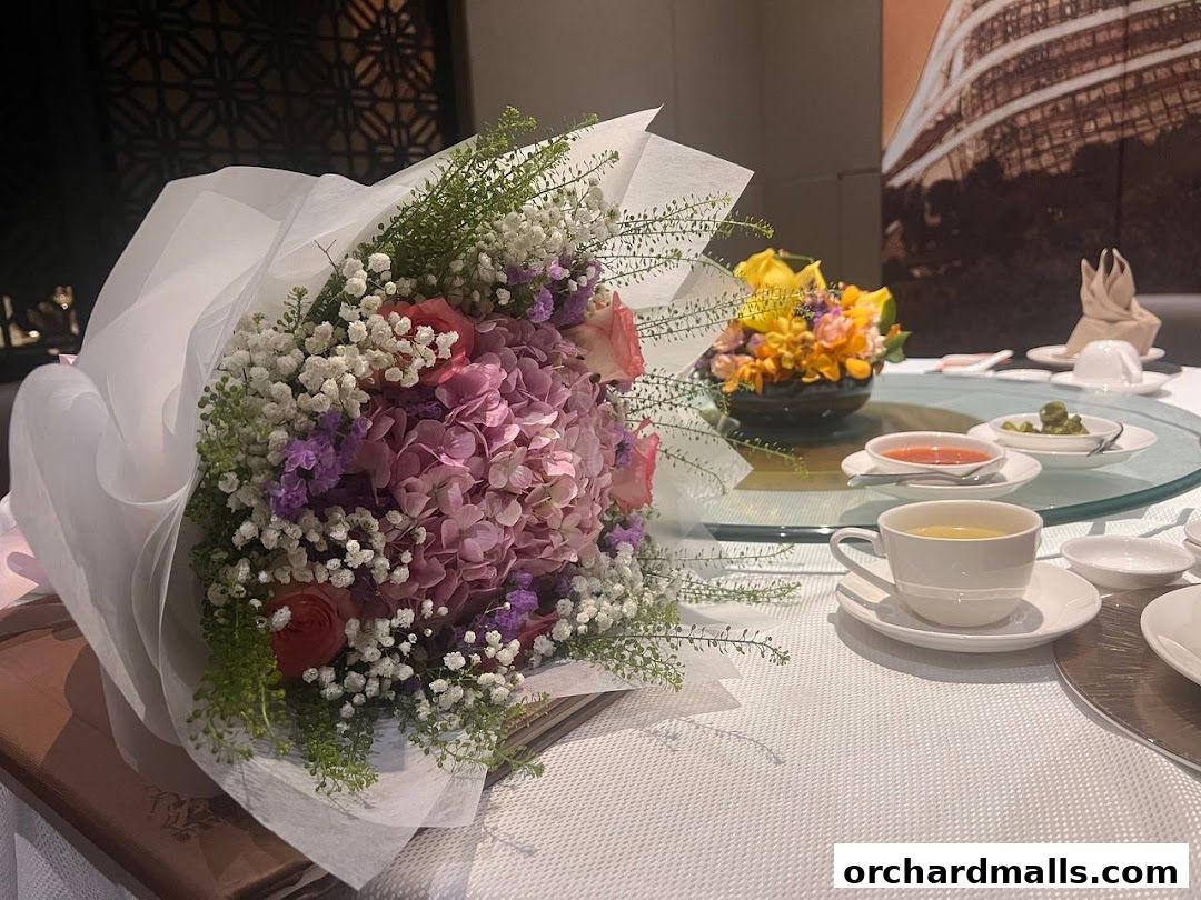 A beautiful bouquet of pink and purple flowers sits on a table with a cup of tea.