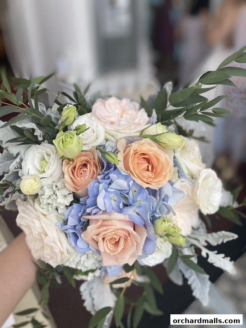 A hand holding a beautiful bouquet of roses, hydrangeas, and greenery.