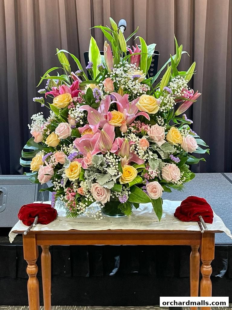 A large, elaborate floral arrangement with pink lilies and roses on a table.
