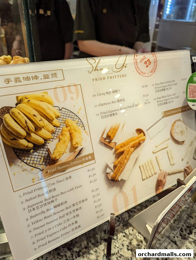 A menu board displaying various fried fritters and drinks with prices.