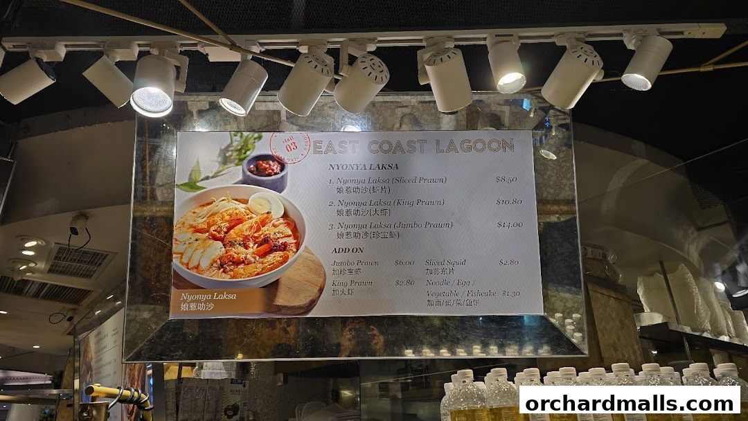 A menu board for East Coast Lagoon featuring Nyonya Laksa with various prawn options and add-ons.
