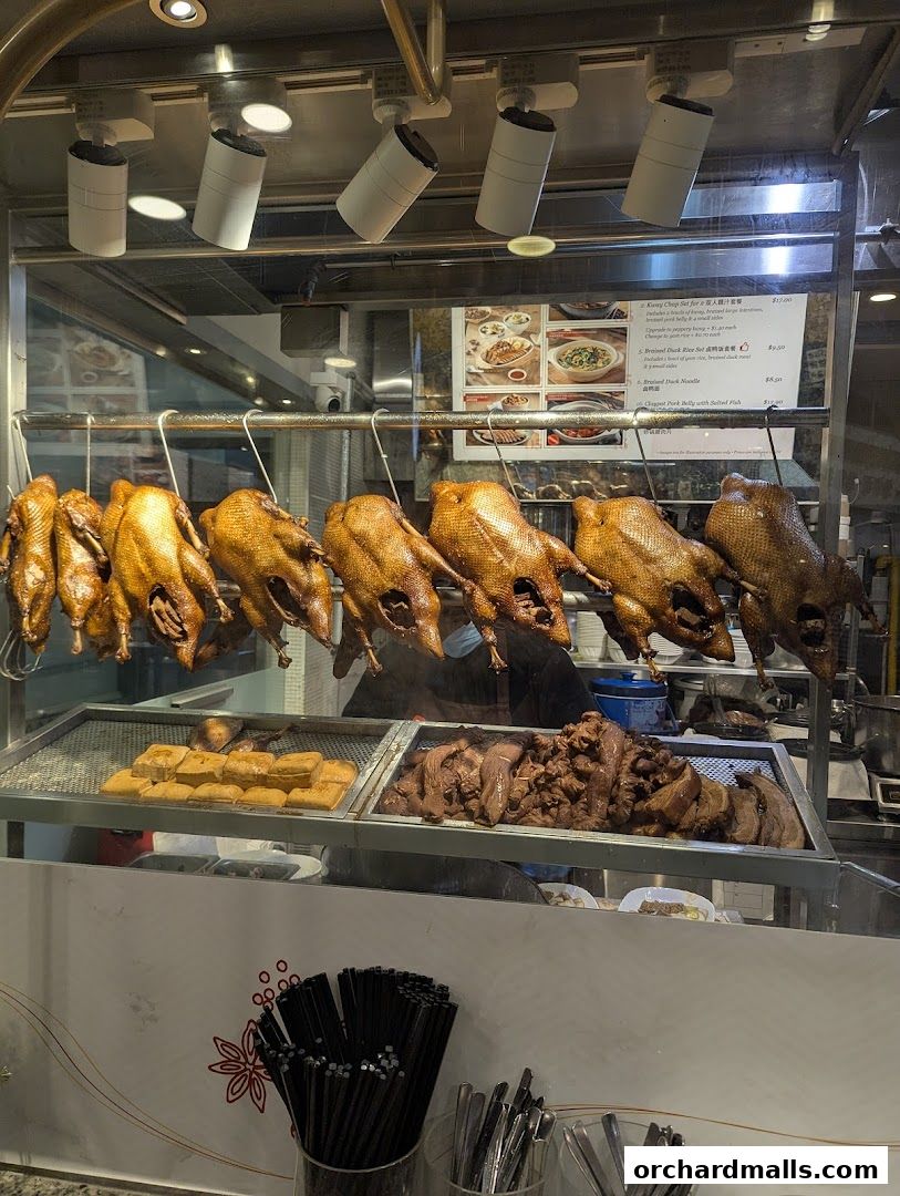 A display of roasted ducks and other meats, with a menu visible in the background.