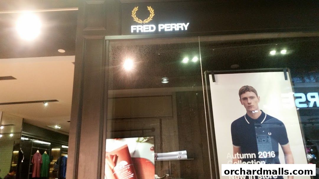 Fred Perry shop front with a display of clothing and a model wearing a polo shirt.