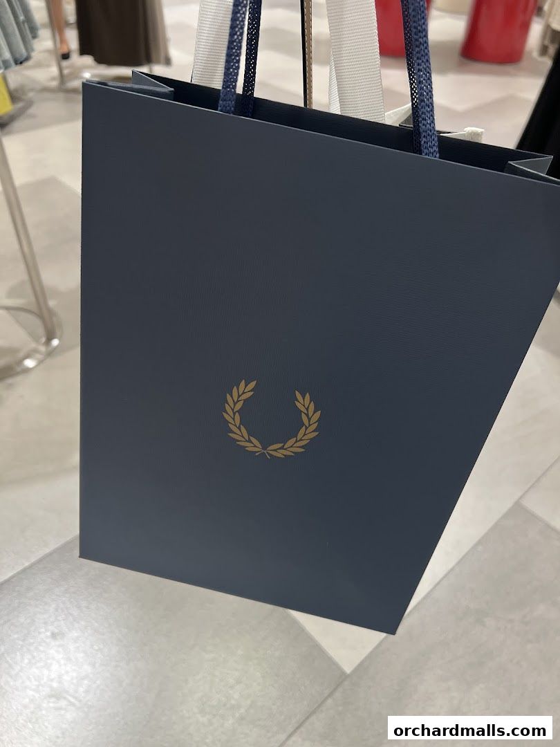 A dark blue Fred Perry shopping bag with a gold laurel wreath logo.
