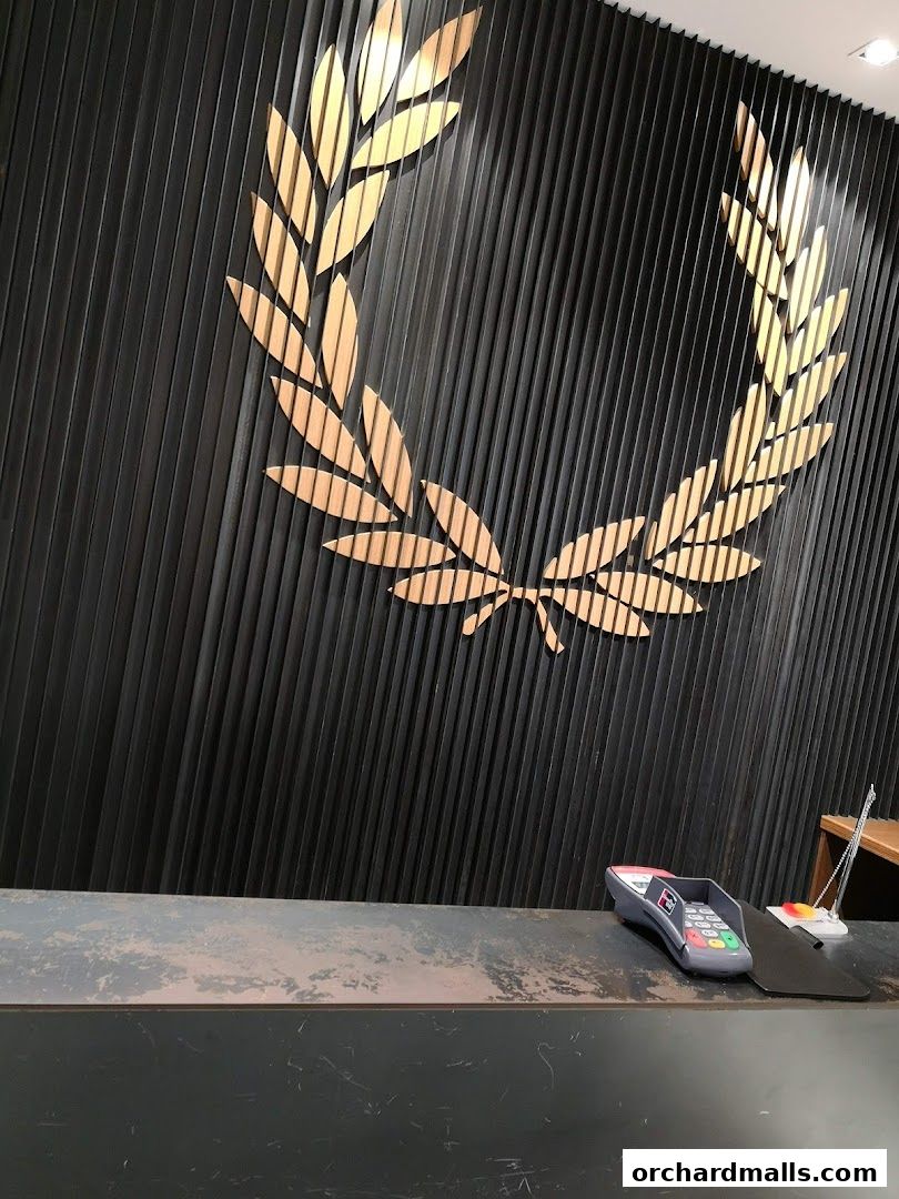 A close-up of a black wall with a golden laurel wreath logo and a payment terminal on a counter.