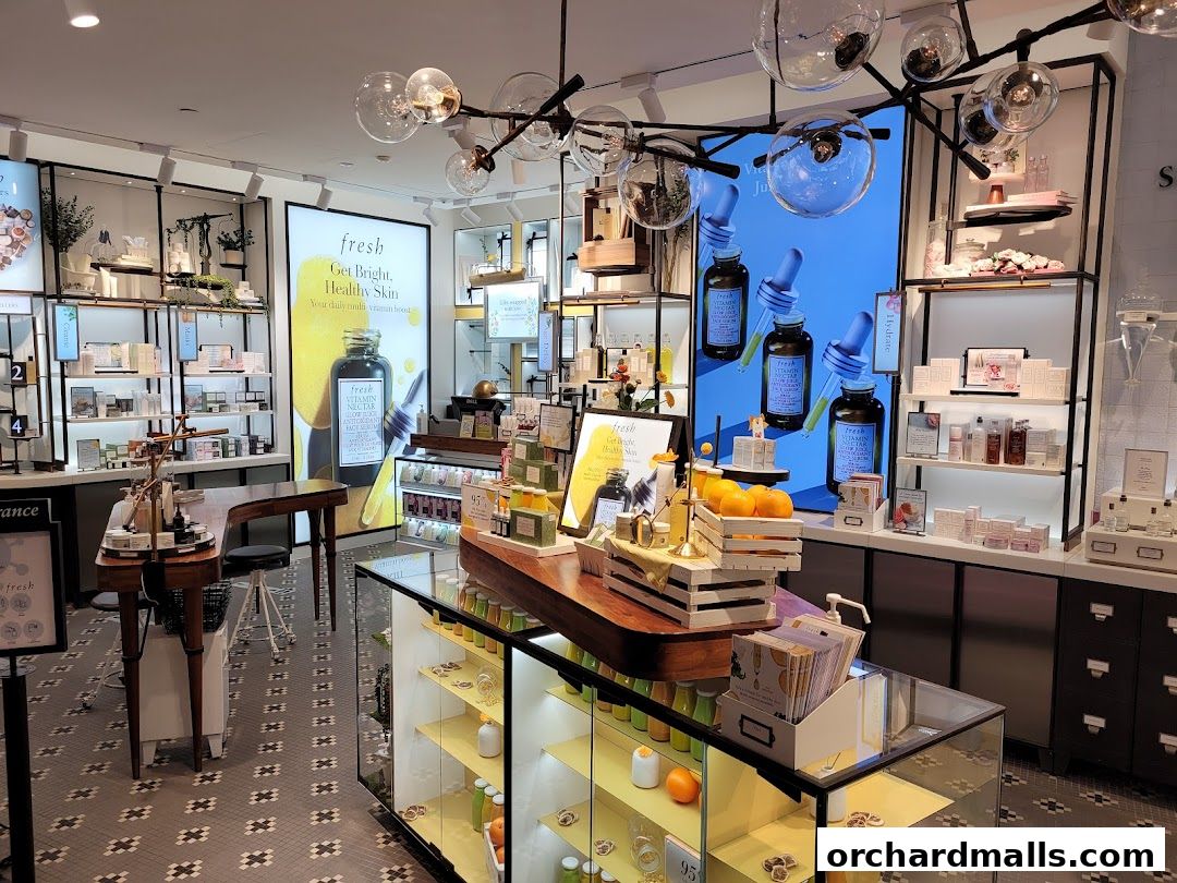 Interior of a Fresh cosmetics store with skincare products displayed on shelves and a digital advertisement.