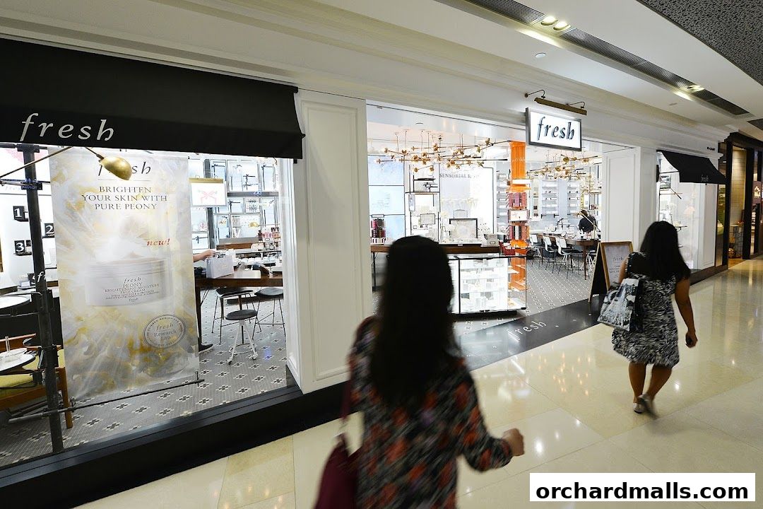 The exterior of a Fresh cosmetics store with a large banner advertising a peony-infused product.