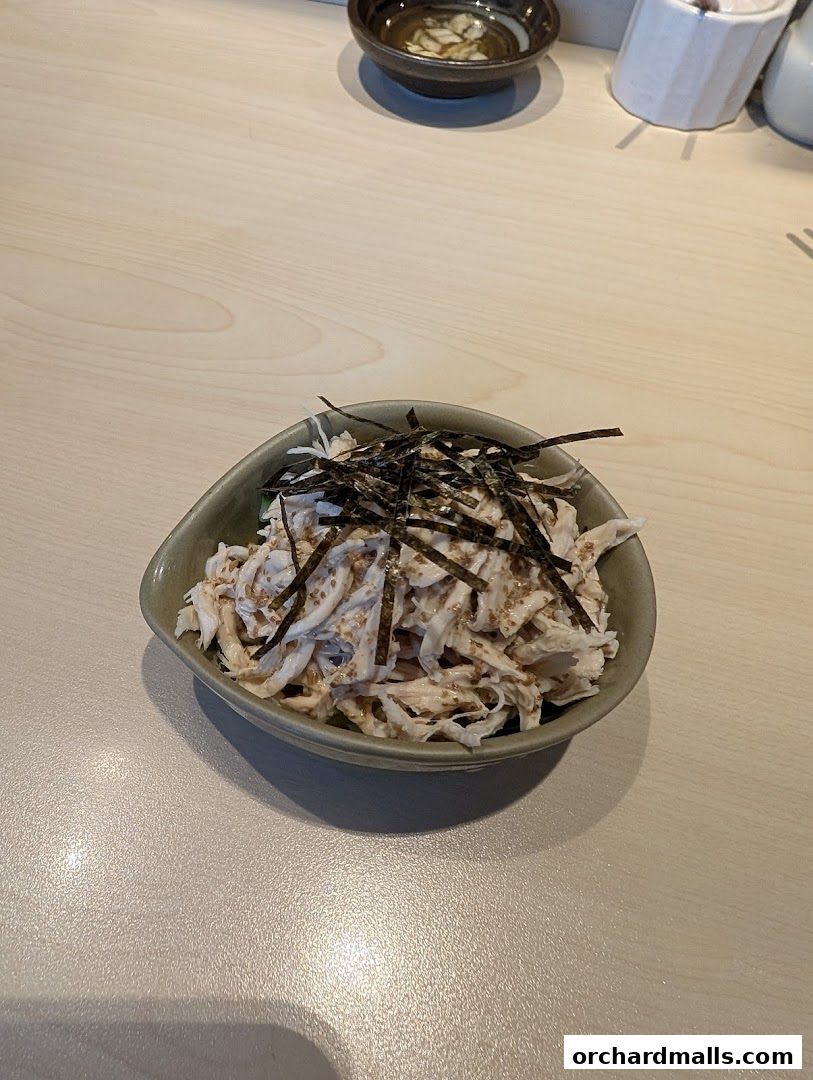 A bowl of shredded chicken salad with seaweed and sesame seeds.