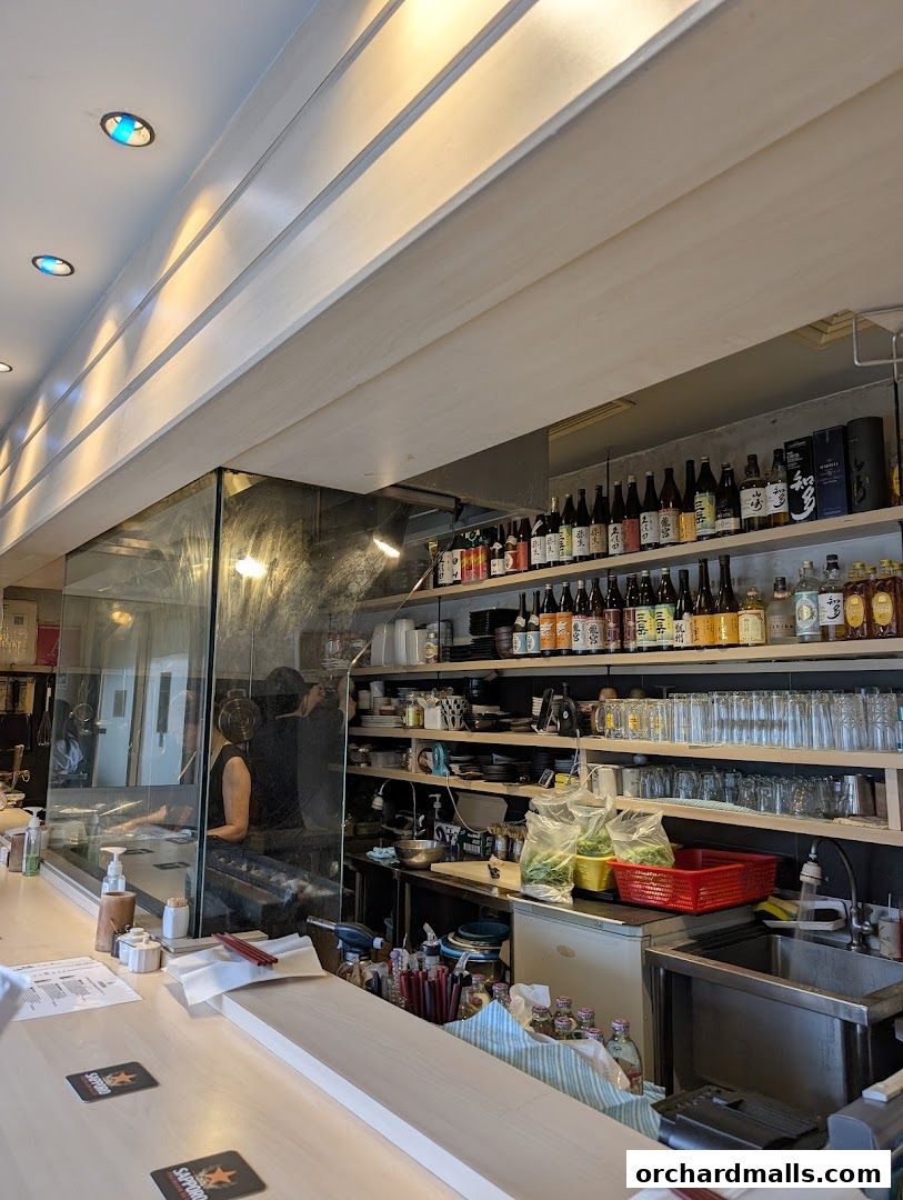Interior view of a Japanese dining establishment with a bar and shelves stocked with bottles and glassware.