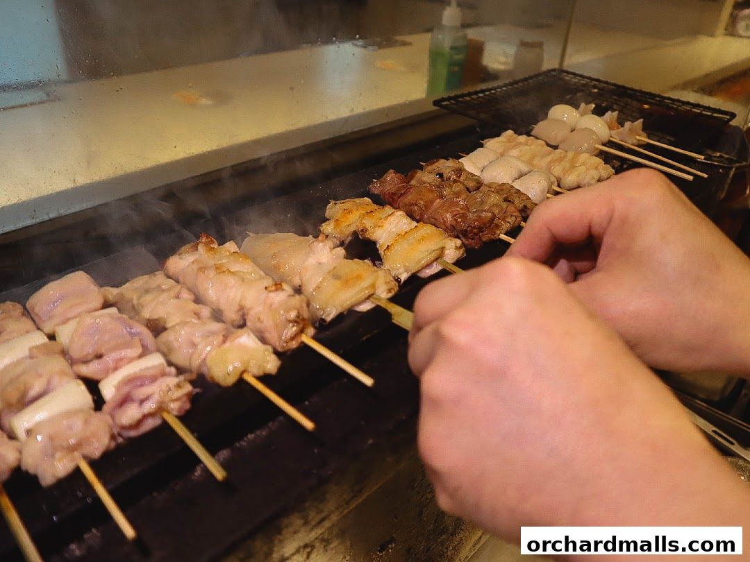 Chef grilling various skewers of meat and seafood over a hot grill.