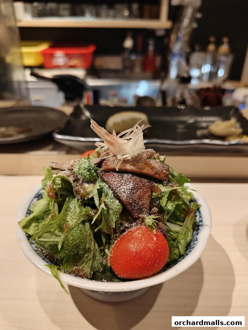 A delicious salad with grilled meat, fresh greens, and a cherry tomato, garnished with ginger.
