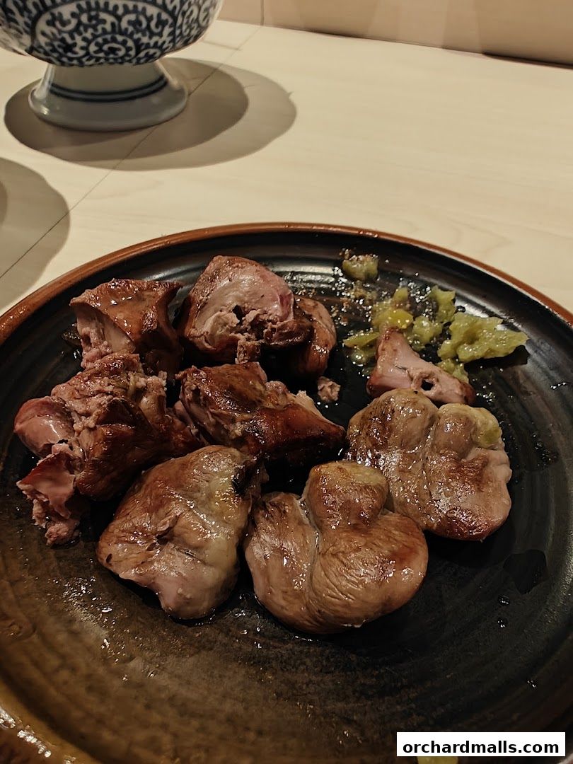 A plate of grilled yakitori skewers with a side of green relish.