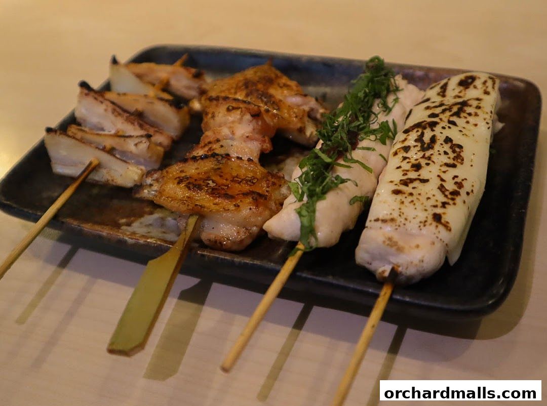 A plate of delicious yakitori skewers, grilled to perfection, served on a dark platter.