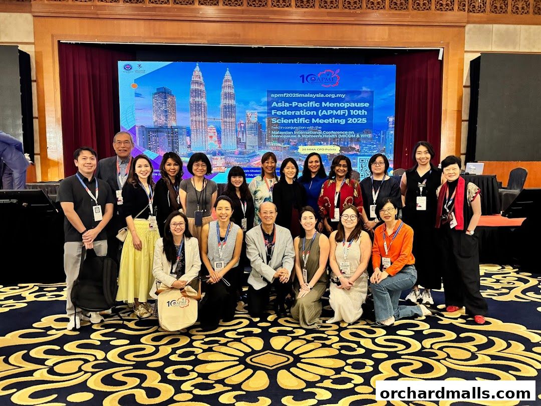 A group of people pose for a photo in front of a screen displaying a conference title.