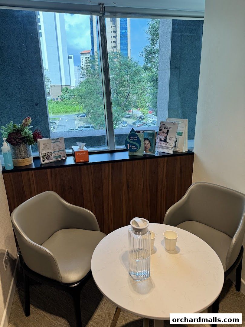 A waiting area with chairs, a table, and brochures by a window.