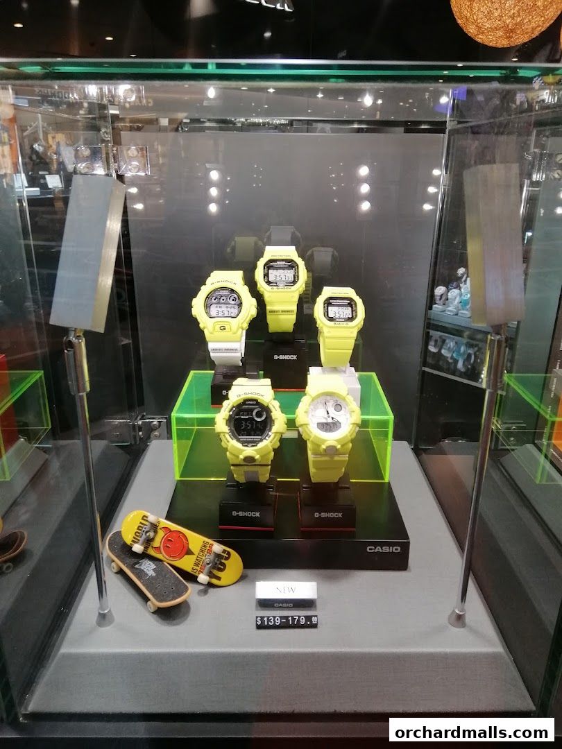 A display case showcasing yellow G-Shock watches and miniature skateboards.
