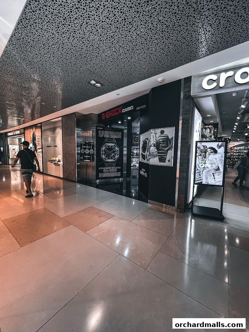The G-SHOCK CASIO store entrance with watches displayed and a person walking by.