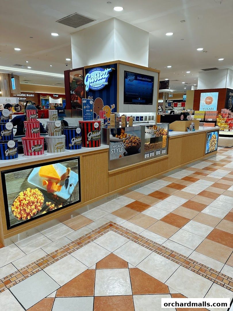 A Garrett Popcorn Shops kiosk displaying various popcorn tins and promotional images.