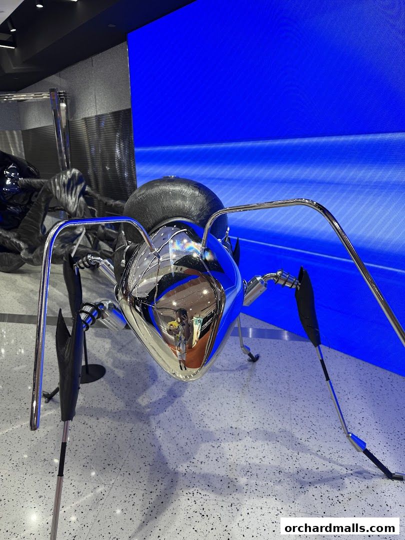 A striking chrome sculpture of an ant with a reflective surface in a modern retail space.