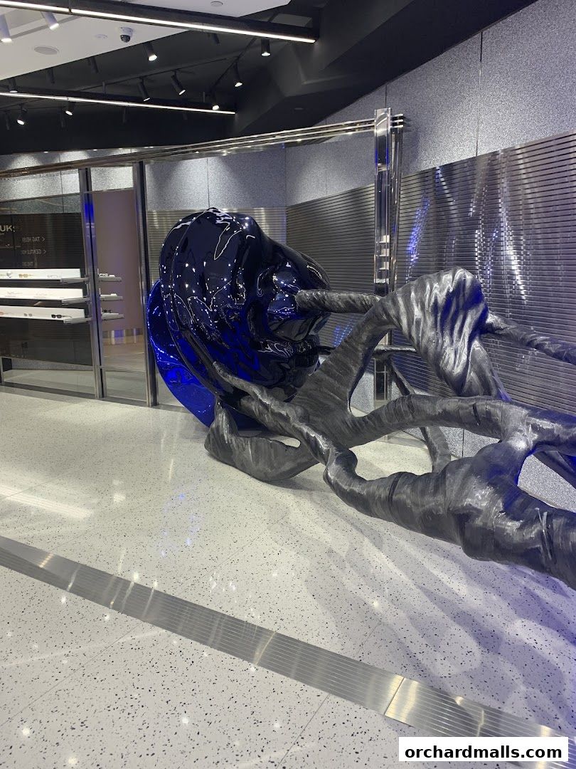 Interior of a modern retail store with a large, abstract sculpture and display shelves.