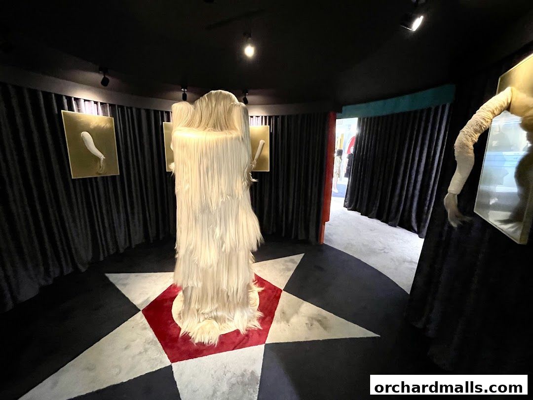 An art installation with a furry sculpture and abstract art pieces in a dark, theatrical setting.