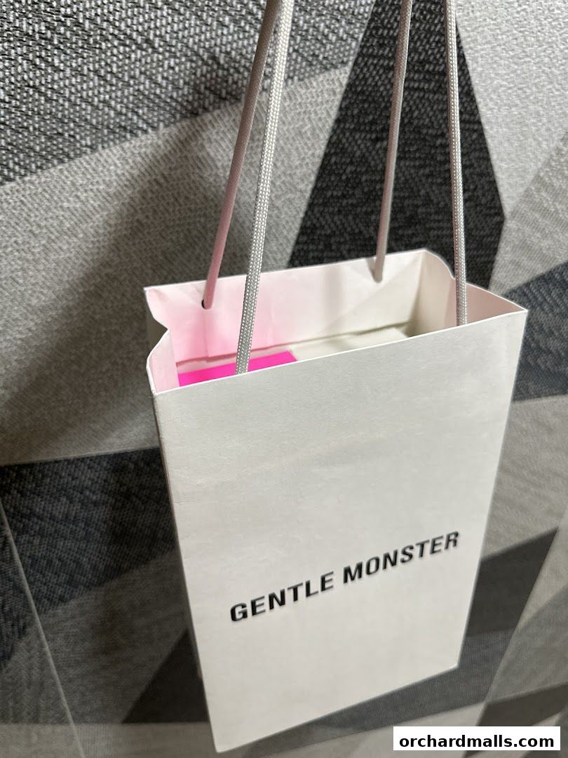 A white shopping bag with 'GENTLE MONSTER' logo and pink accents.