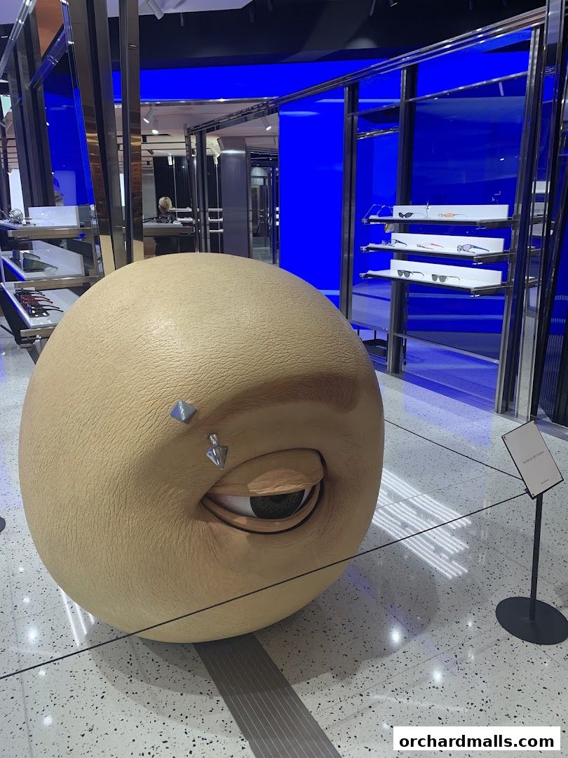 A large, spherical art installation with an eye and piercings inside a modern retail store.