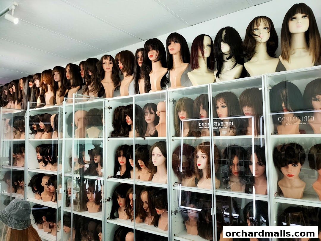 A wide selection of wigs displayed on mannequins in a retail store.