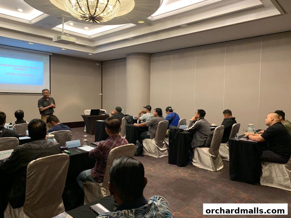 A trainer presents anti-counter terrorism strategies to an audience in a conference room.