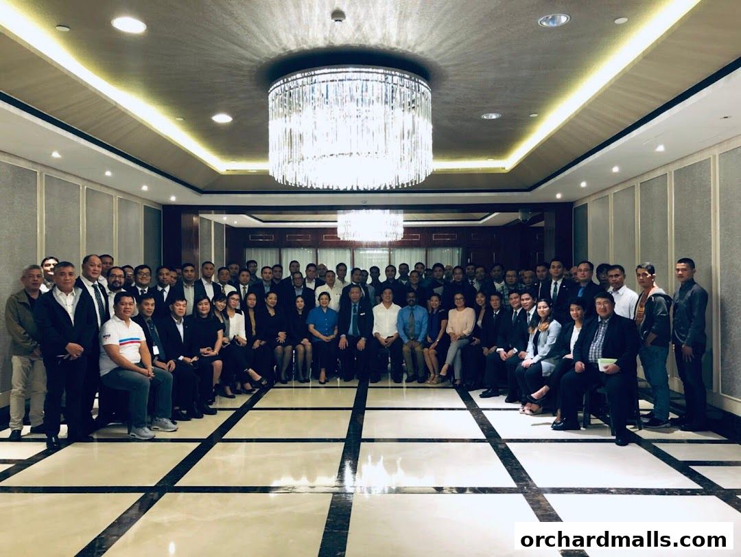 A large group of people in formal attire pose for a photo in a well-lit room.