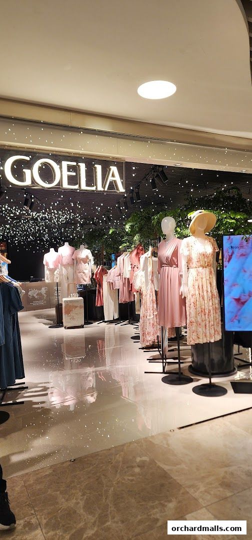 A fashion store display featuring mannequins in pink dresses and clothing racks.