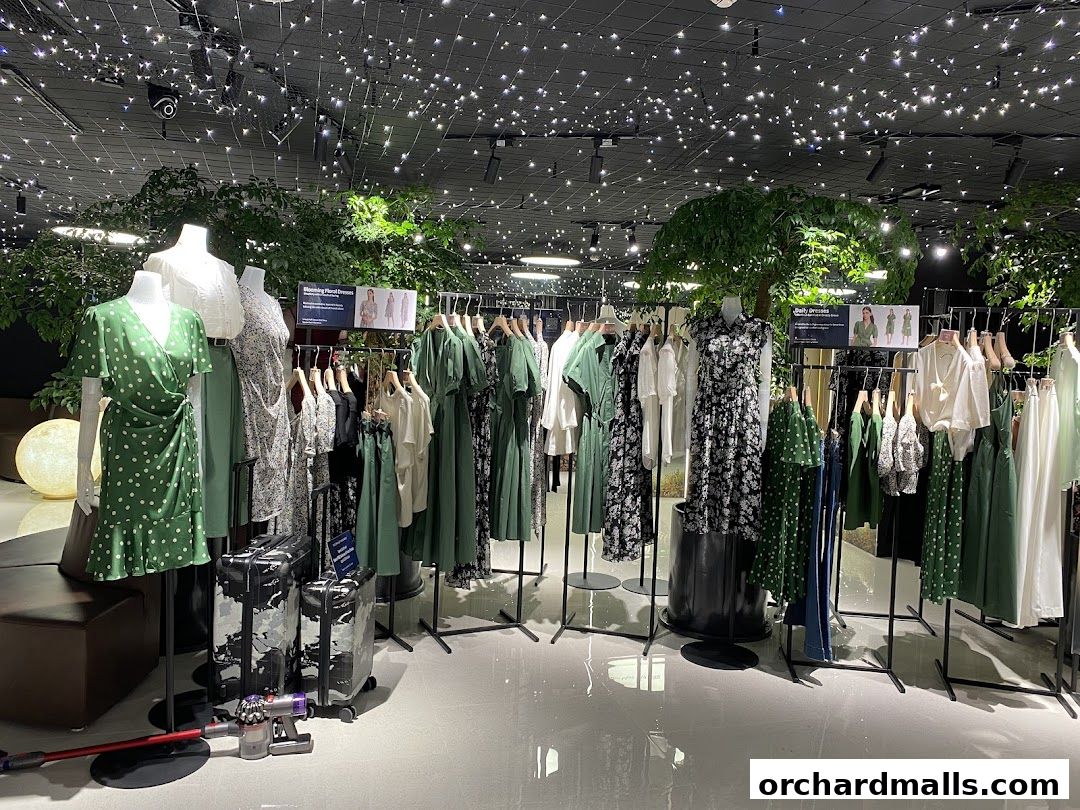 A fashion store interior with mannequins displaying dresses and racks of clothing.