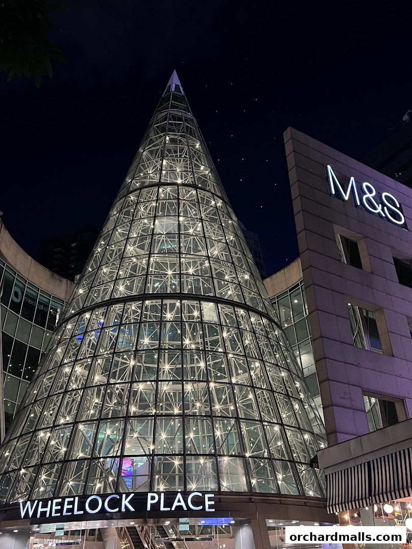 Wheelock Place shopping mall illuminated at night with a distinctive glass cone structure.