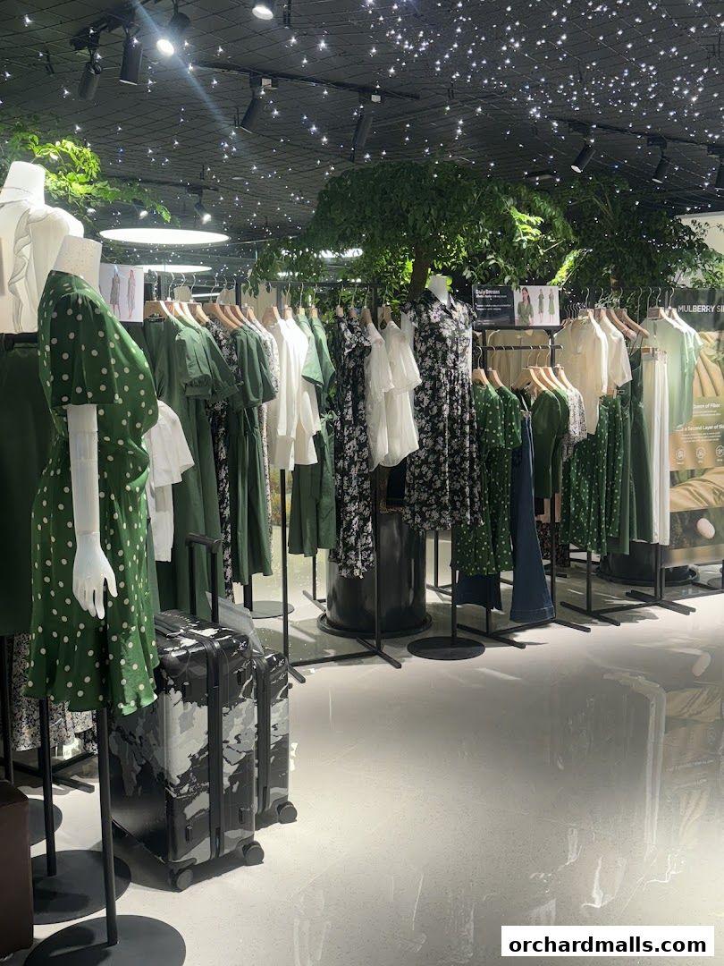Interior of a clothing store with mannequins and racks of green and white dresses.