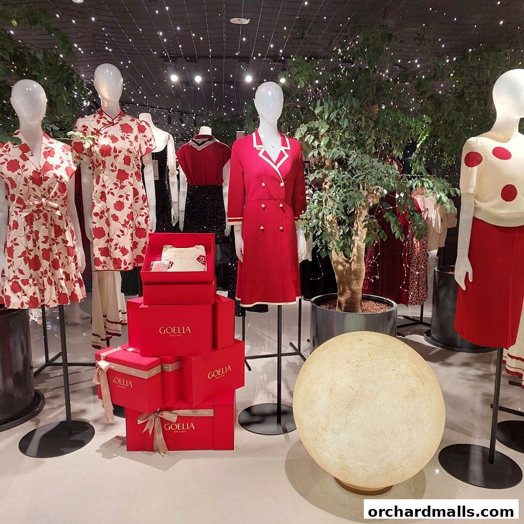 Mannequins display red and white floral dresses and a red blazer with gift boxes.