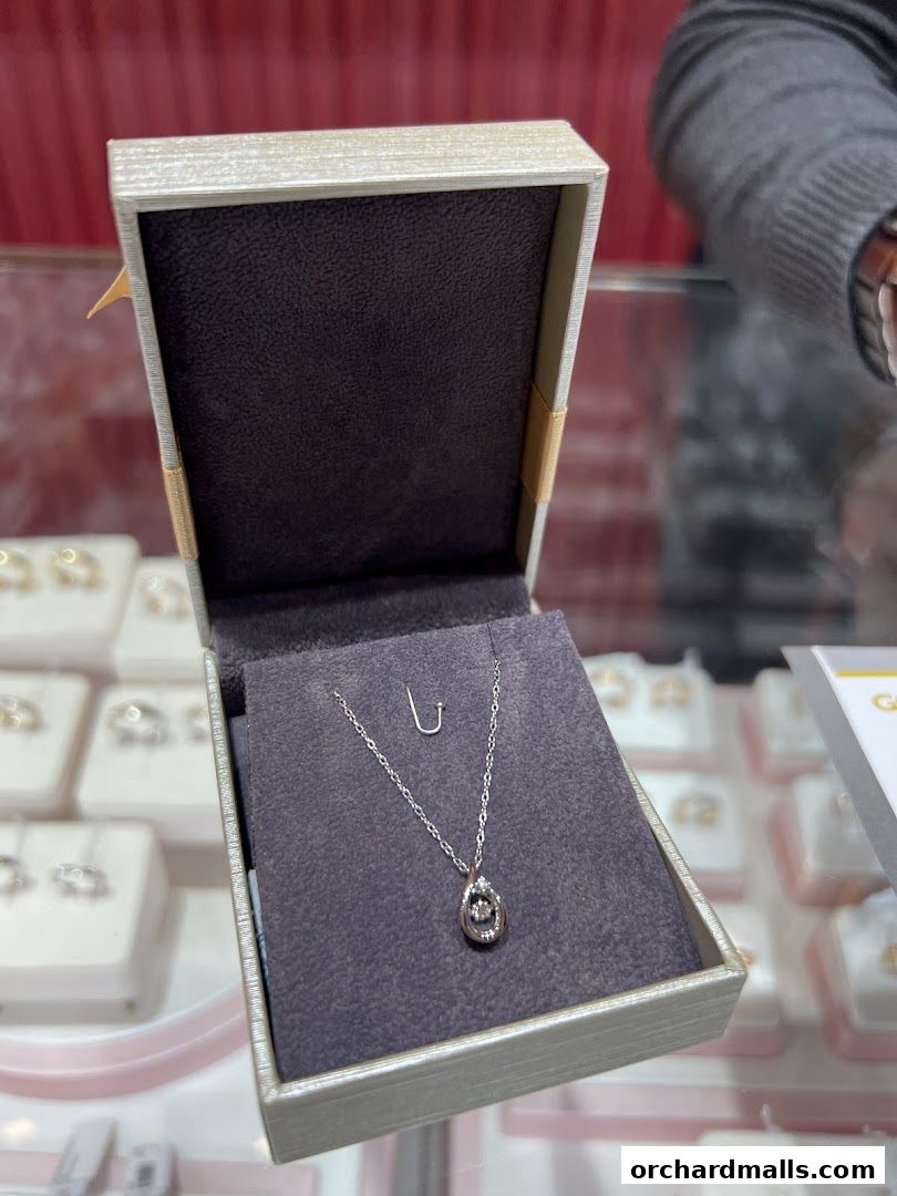 A diamond pendant necklace displayed in an open jewelry box.