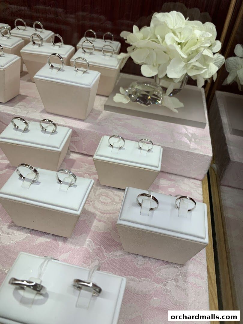 A display of elegant wedding rings on white stands, adorned with white flowers and a crystal.
