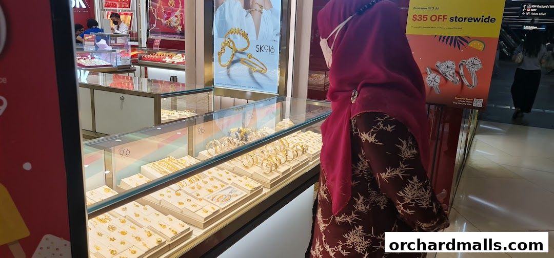 A customer browses a display of gold jewelry at Goldheart Jewelry, ION Orchard.