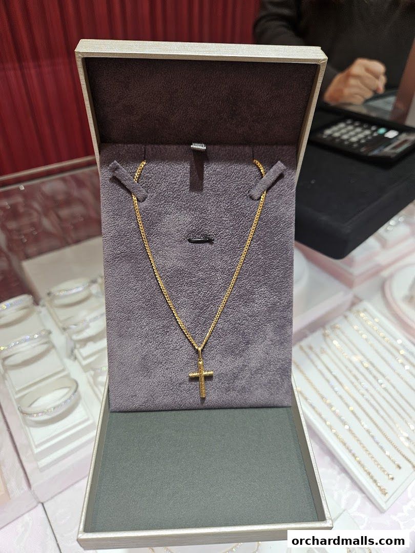 A gold cross pendant necklace displayed in an open jewelry box.