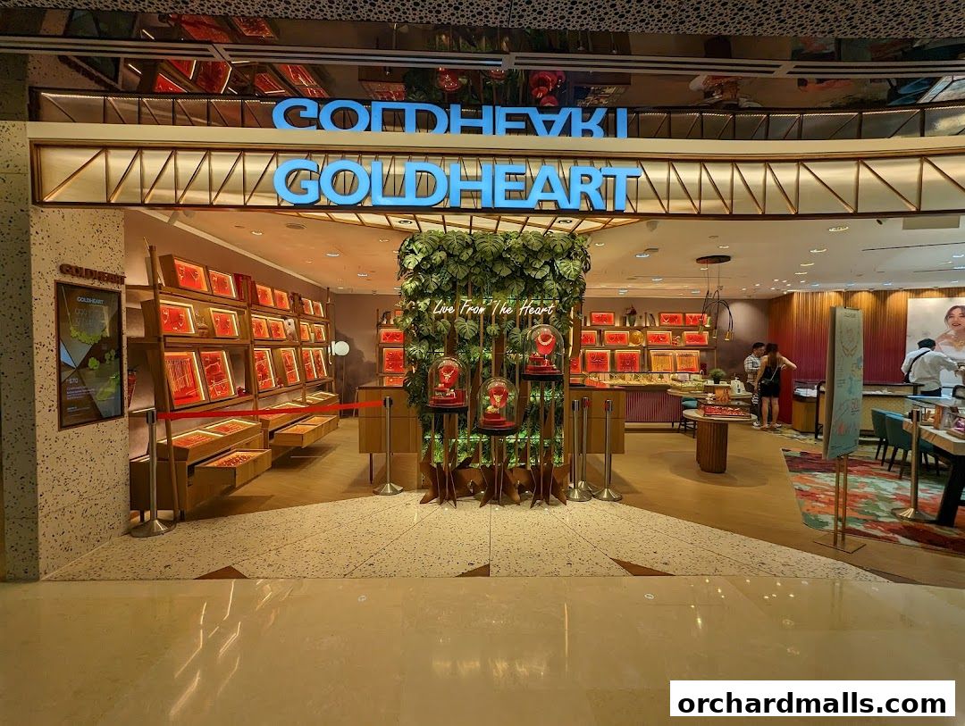 The entrance of a Goldheart Jewelry store with displays of jewelry and a green plant feature.