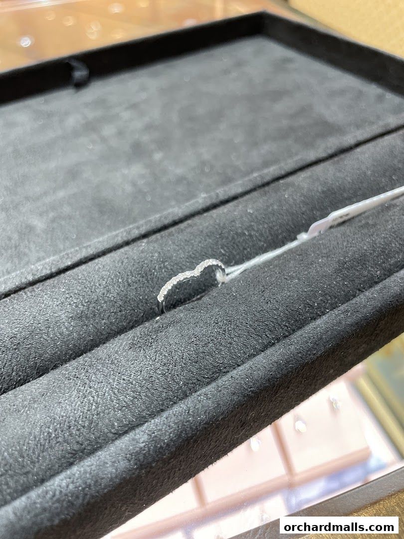 A delicate diamond ring shaped like a heart, displayed in a velvet jewelry box.