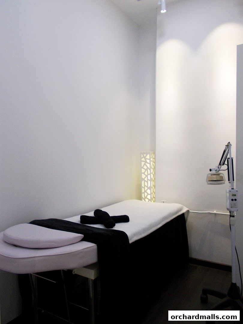 A clean and modern treatment room with a massage bed and therapeutic lamp.