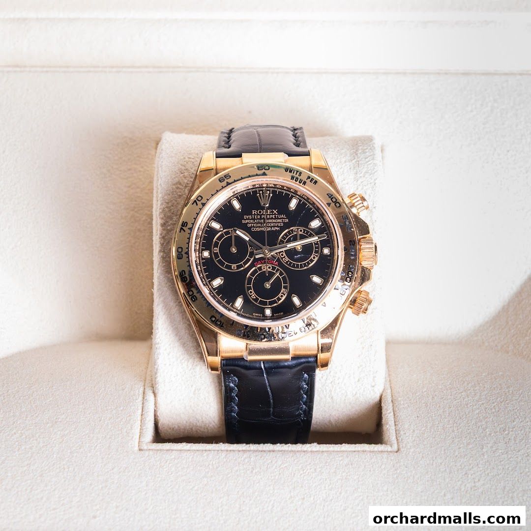 A luxurious gold Rolex Daytona watch with a black dial and leather strap.