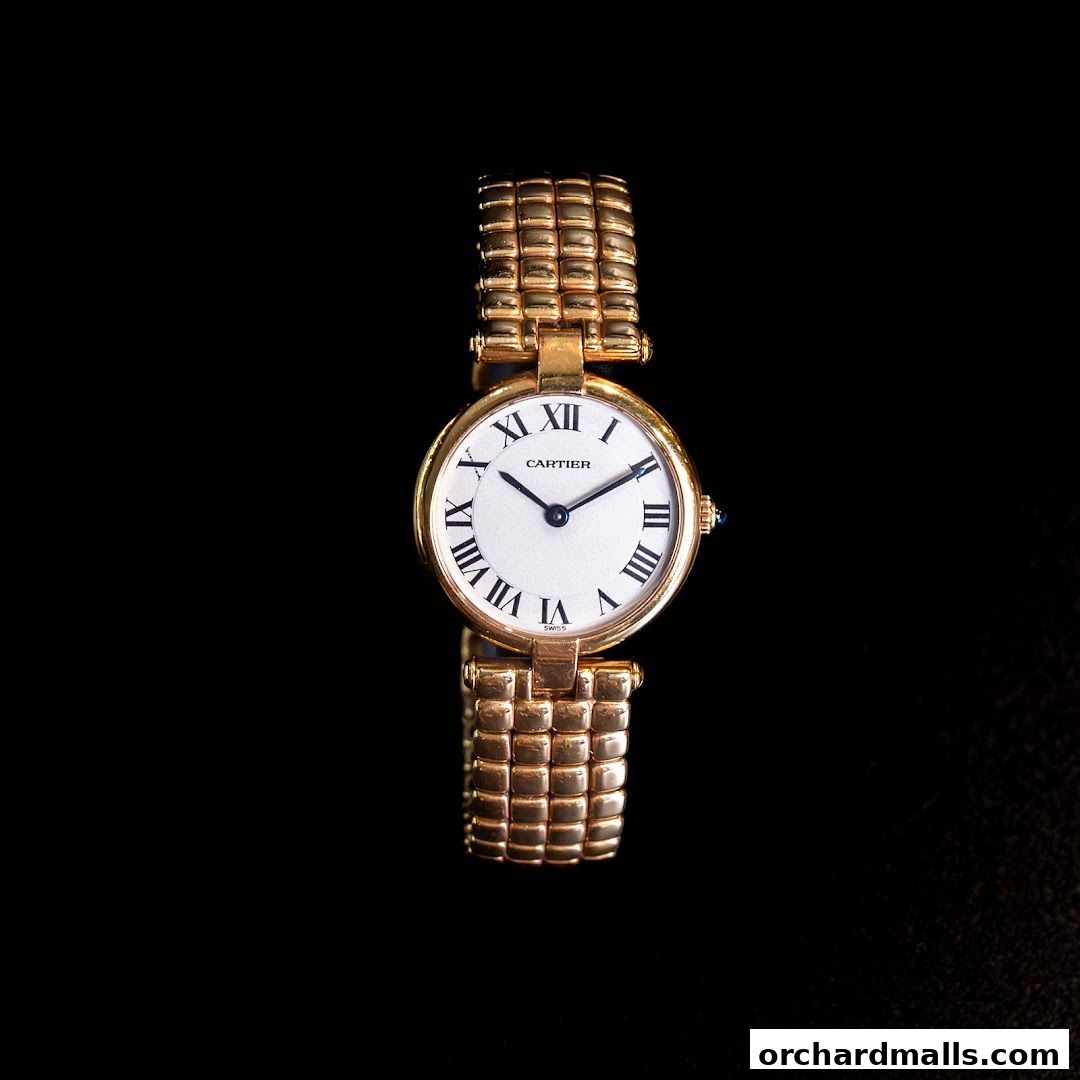 A close-up shot of a luxurious gold Cartier watch with Roman numerals on a black background.